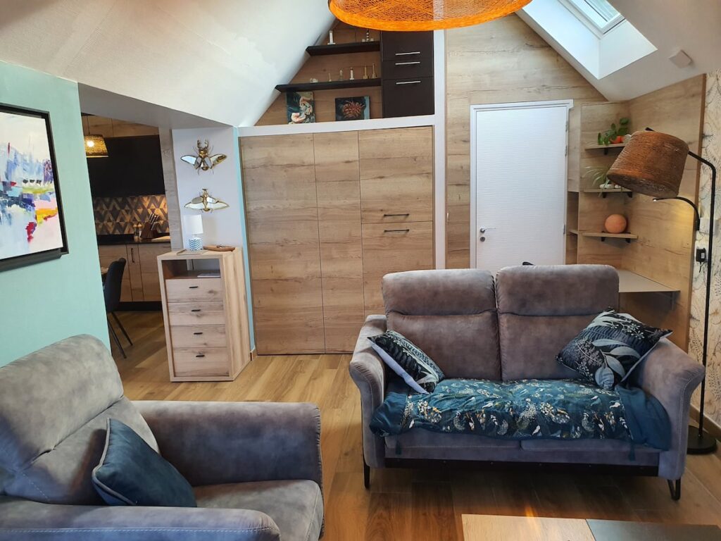 Salon attenant à l' espace repas avec un canapé et un fauteuil "Mobilier de France" et un espace bureau chaleureux doté d' un velux électrique pour une aération de qualité.