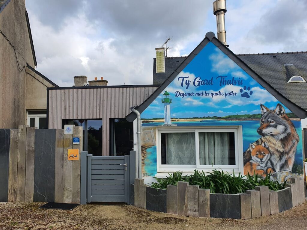 La façade de" Ty Gard Thalvis" est décorée d' une fresque du Graffeur Alexdecograff. "Degemer Mat les 4 pattes!" signifie : "Bienvenue aux 4 pattes!" Deux chiens loups veillent sur le phare et signalent mon engagement pour le droit Animal.
